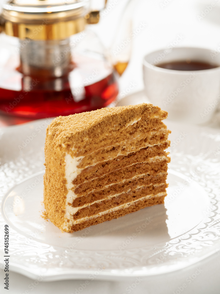 Slice of layered honey cake selective focus. Perfect piece of layered honey cake in restaurant bokeh background. Traditional Russian layer cake Medovik made with honey Slice of layered honey cake selective focus. Perfect piece of layered honey cake in restaurant bokeh background. Traditional Russian layer cake Medovik made with honey