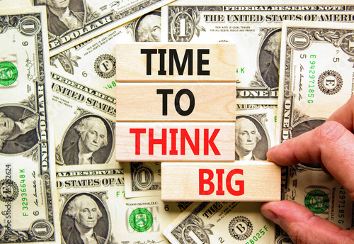 Time to think big symbol. Concept words Time to think big on beautiful wooden block. Beautiful dollar bills background. Businessman hand. Dollar bills. Business time to think big concept. Copy space.