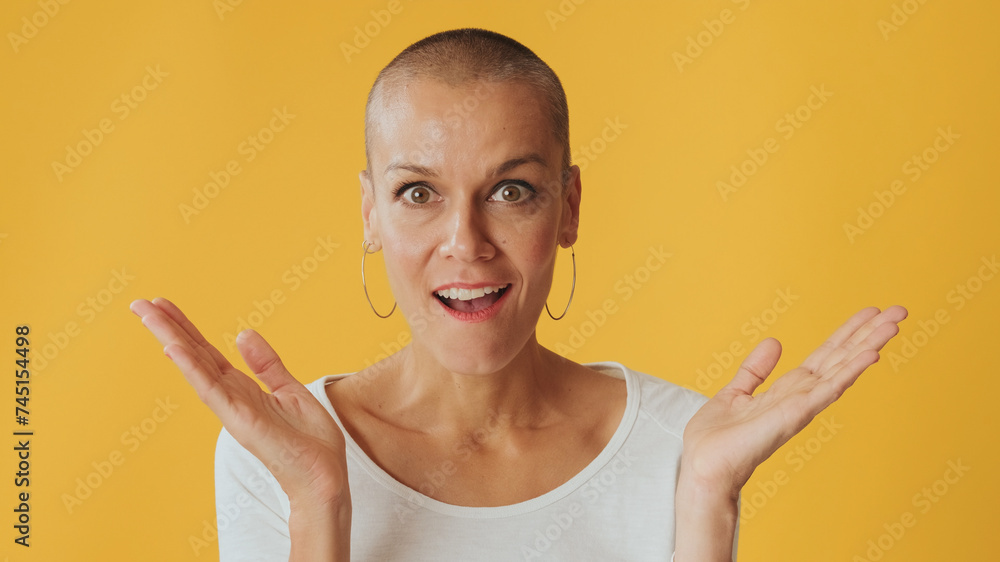 Close-up, shocked young hairless woman, looking at camera with big eyes, says wow, isolated on yellow background in studio Close-up, shocked young hairless woman, looking at camera with big eyes, says wow, isolated on yellow background in studio