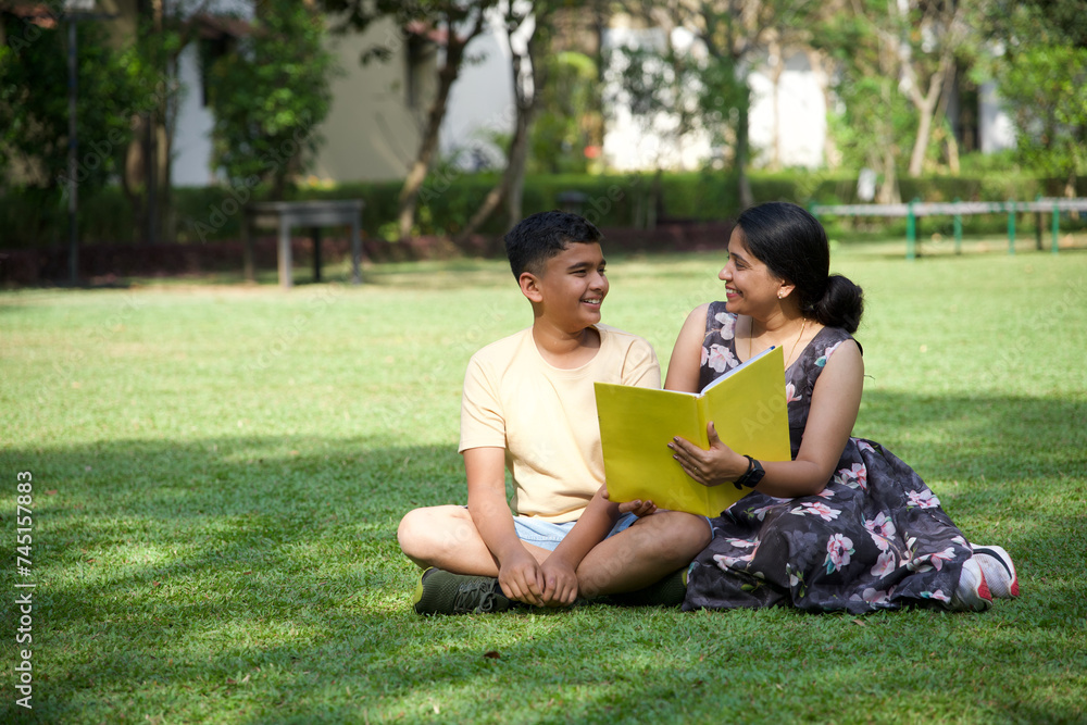 Happy mother and her teenage son spending time together with book Happy mother and her teenage son spending time together with book