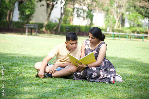 Happy mother and her teenage son spending time together with book  © Ojas