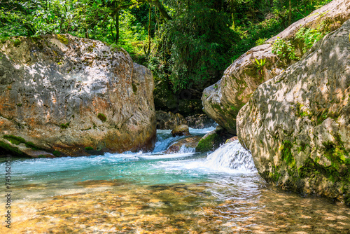 a mountain river with clear water, large rocks and water running between them