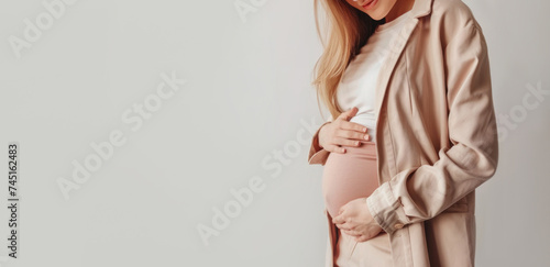banner pregnant woman in a jacket holding her stomach on a light background. Pregnancy, maternity, preparation and expectation.