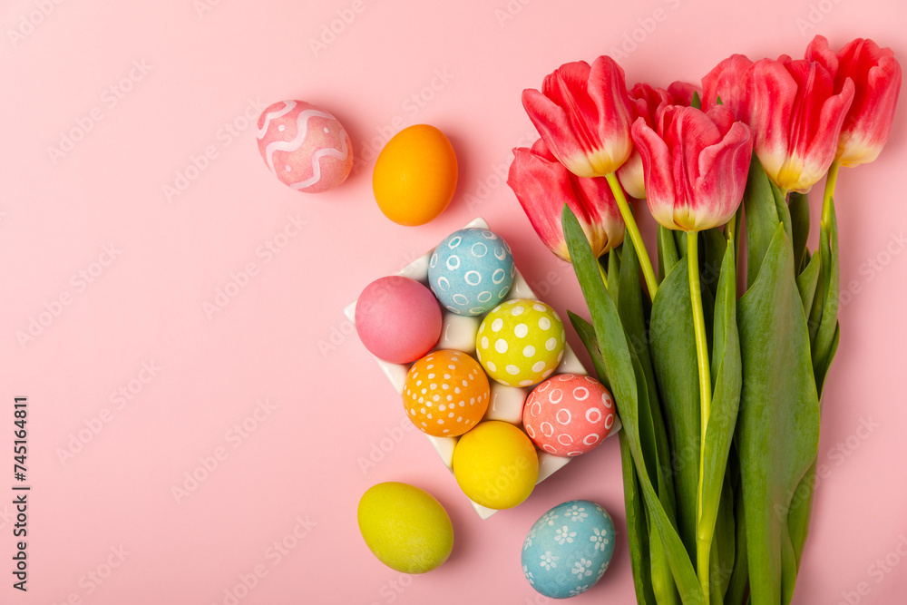 Easter eggs with a bouquet of tulips on a bright pink background. Easter celebration concept. Colorful easter handmade decorated Easter eggs. Place for text. Copy space. Easter eggs with a bouquet of tulips on a bright pink background. Easter celebration concept. Colorful easter handmade decorated Easter eggs. Place for text. Copy space.