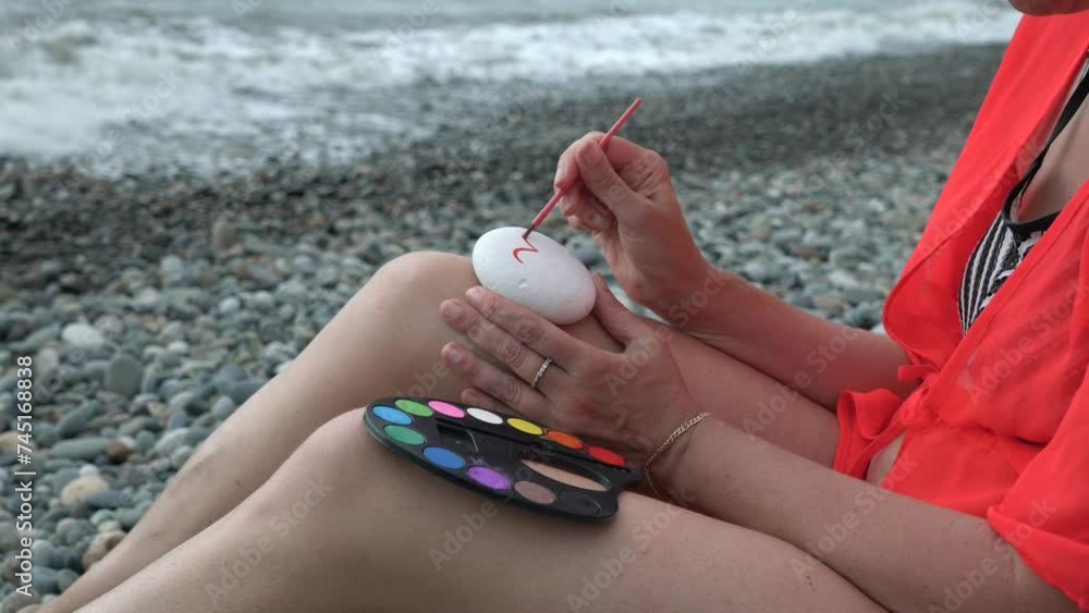 Young woman painting with watercolors on the beach. Hobby and leisure ...