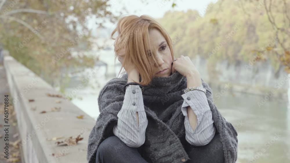 depressed daydreaming and sad woman portrait: sitting on a wall in the city depressed daydreaming and sad woman portrait: sitting on a wall in the city