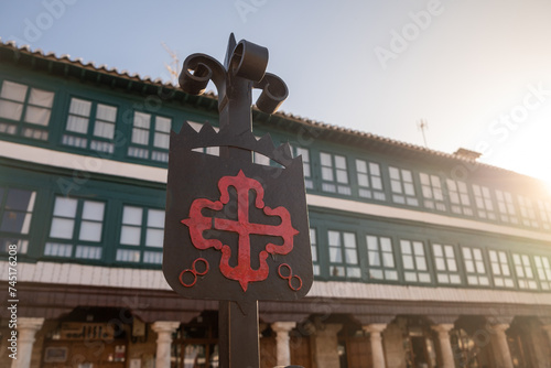 Old Iron Emblem of the Order of Calatrava iluminated by the morning sun. red Greek cross with fleur-de-lis at the ends, in the Plaza Mayor of Almagro, Ciudad Real, Castila La Mancha, Spain, Europe. photo