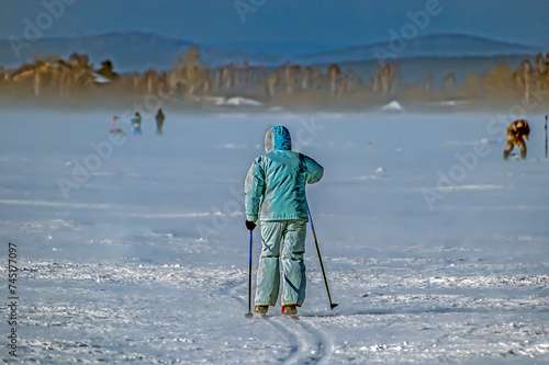 A woman is skiing on the snow-covered ice of a lake on a winter day
