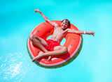 Joyful kid float in pool on watermelon ring, view from above