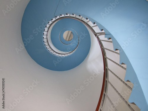 a spiral staircase in a building, blue and white, the view goes from bottom to top