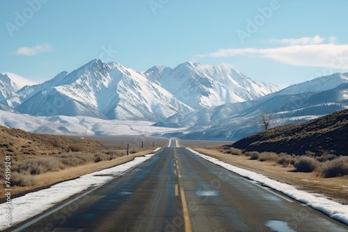 A scenic view of an empty road with snow-capped mountains in the background. Perfect for winter travel concepts.