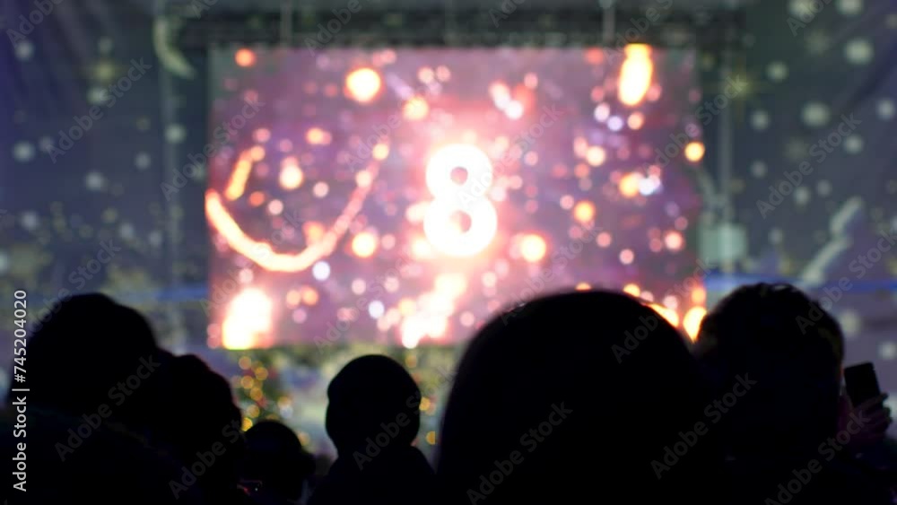 People look at a large television screen, on which the numbers are counting down. People look at a large television screen, on which the numbers are counting down.