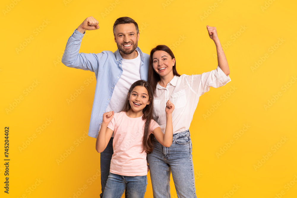 Happy European Family Showing Biceps Over Yellow Studio Background