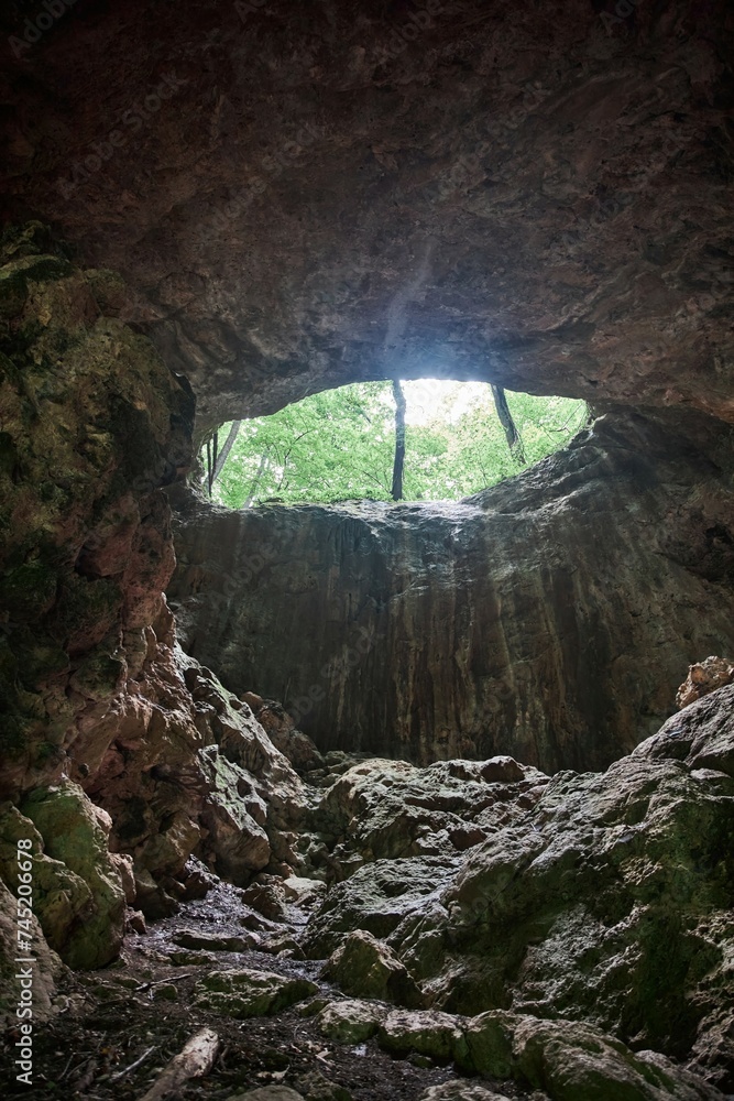 Large vertical cave, entrance from above, mountain landscape