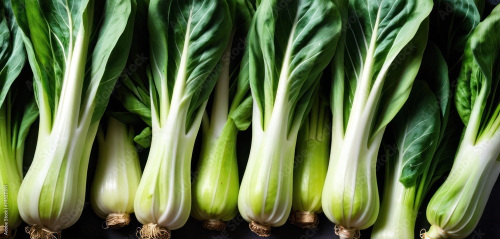 a bunch of celery sitting on top of a table next to a pile of leafy green vegetables. a bunch of celery sitting on top of a table next to a pile of leafy green vegetables.