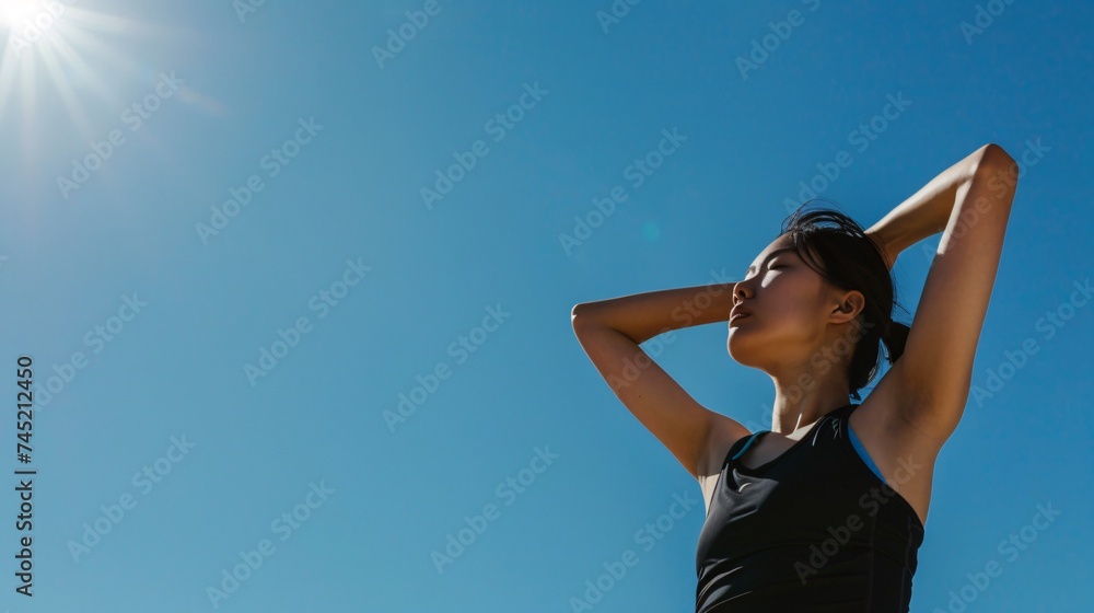 Copyspace beside an Asian woman stretching blue sky above reflecting a journey of fitness and peace Copyspace beside an Asian woman stretching blue sky above reflecting a journey of fitness and peace