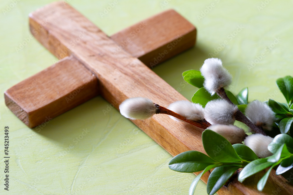 Wooden cross with boxwood twigs and catkins on green background. Palm Sunday concept Wooden cross with boxwood twigs and catkins on green background. Palm Sunday concept