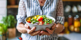 Senior healthy lifestyle living eating habits long life concept. Close-up hands of senior woman in shirt holding a healthy vegetable fresh salad bowl on blurred kitchen background