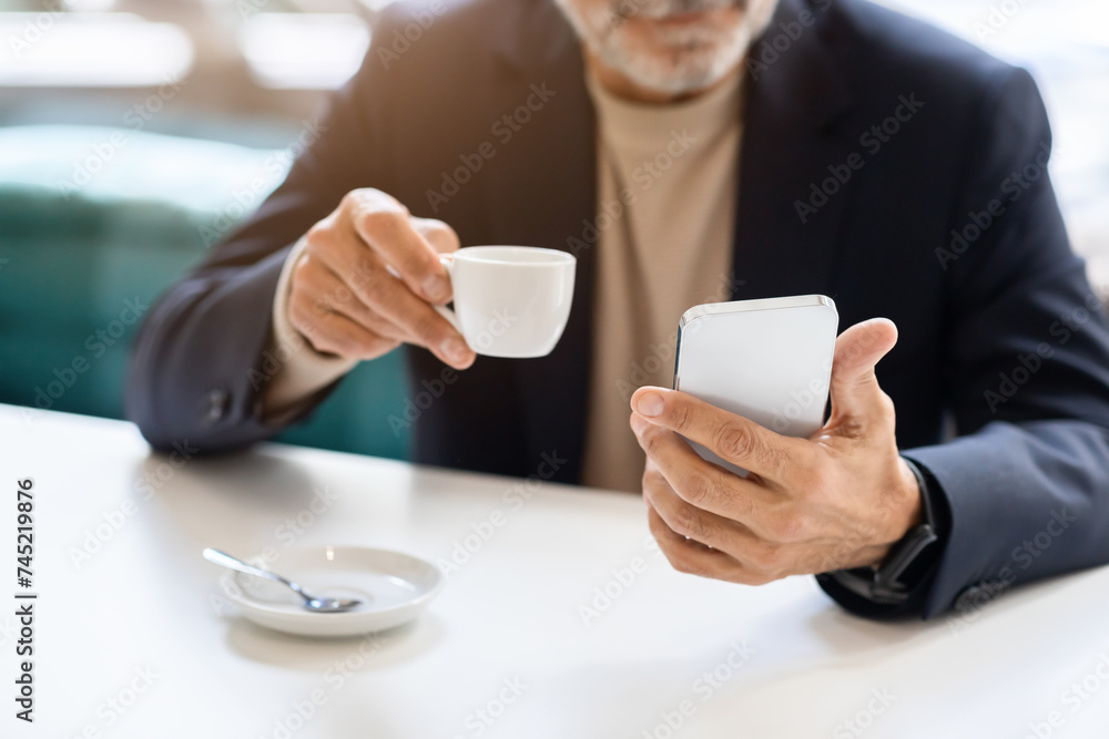 Close-up of a man's hands as he multitasks with a white espresso cup in one hand Close-up of a man's hands as he multitasks with a white espresso cup in one hand