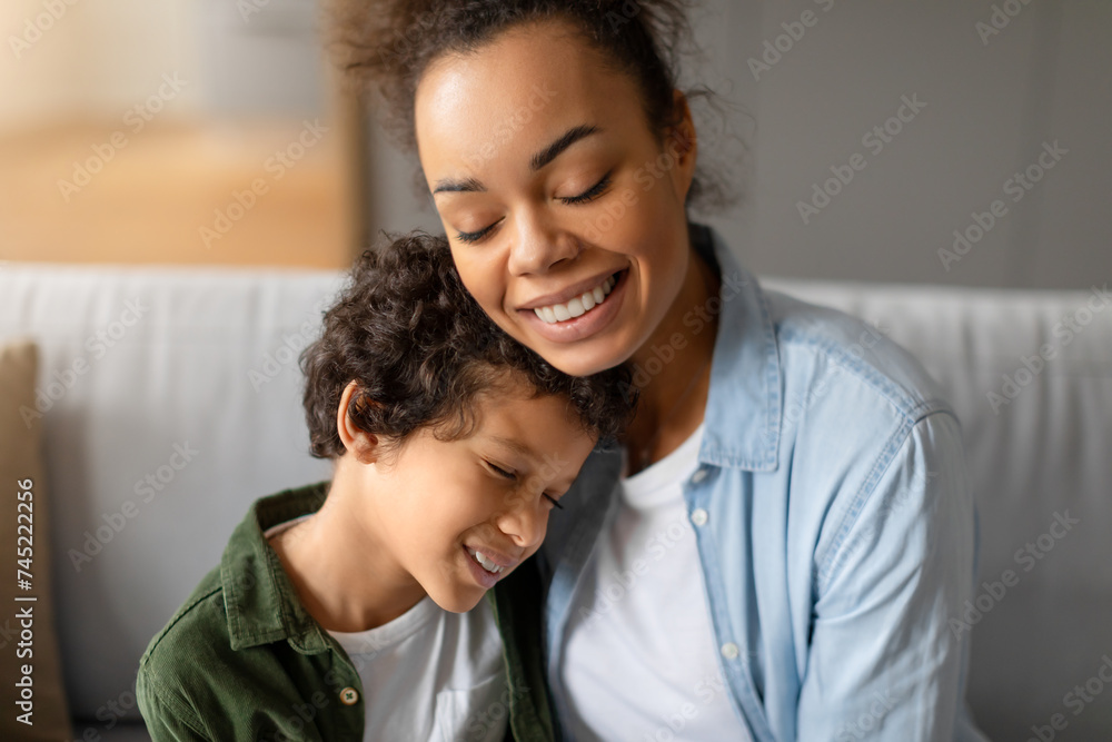 Affectionate black mother hugging smiling son, sharing tender moment Affectionate black mother hugging smiling son, sharing tender moment