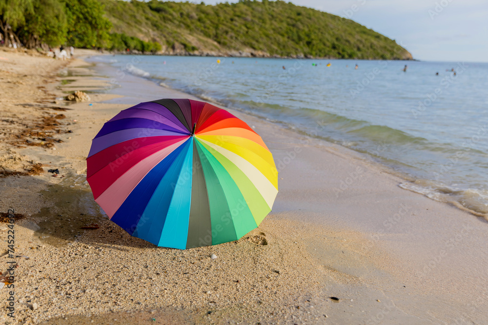 Rainbow color of umbrella on white sand beach. colorful umbrella  in the beach on a sunny summer day. colorful beach umbrella. Useful as cover art or background