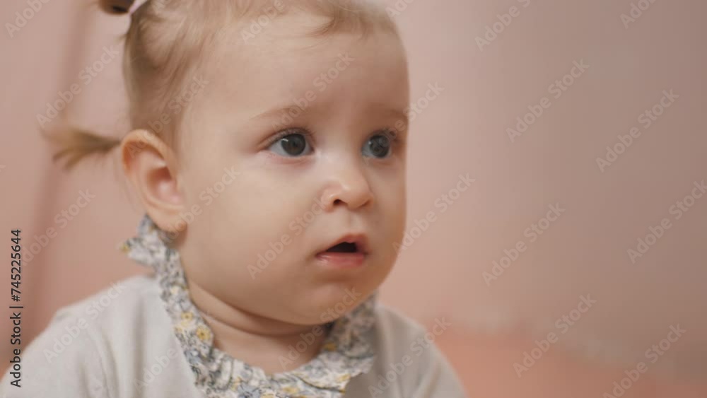 Portrait of a little baby girl thoughtfully looking ahead. She looks dreamily. Cute little girl. Cute hairstyle