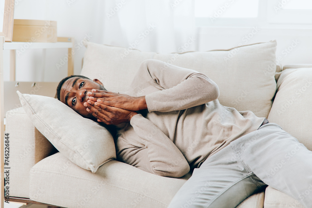 Obraz premium Stressed African American Man Suffering from Headache on Couch at Home