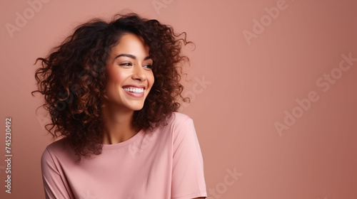 Close up of young woman with white skin, brown hair, wavy hair and a clear rose gold orange t shirt, isolated in a light orange studio. Portrait person. © Sittipol 