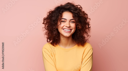 Close up of young woman with white skin, brown hair, wavy hair and a clear  yellow t shirt, isolated in a light  rose gold studio. Portrait person. © Sittipol 