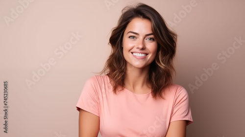 Close up of young woman with white skin, brown hair, wavy hair and a clear rose gold orange t shirt, isolated in a light orange studio. Portrait person.