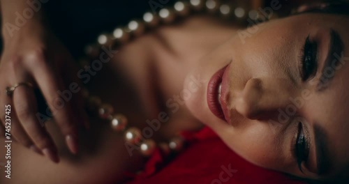 Seductive woman in pearl necklace lying on bed