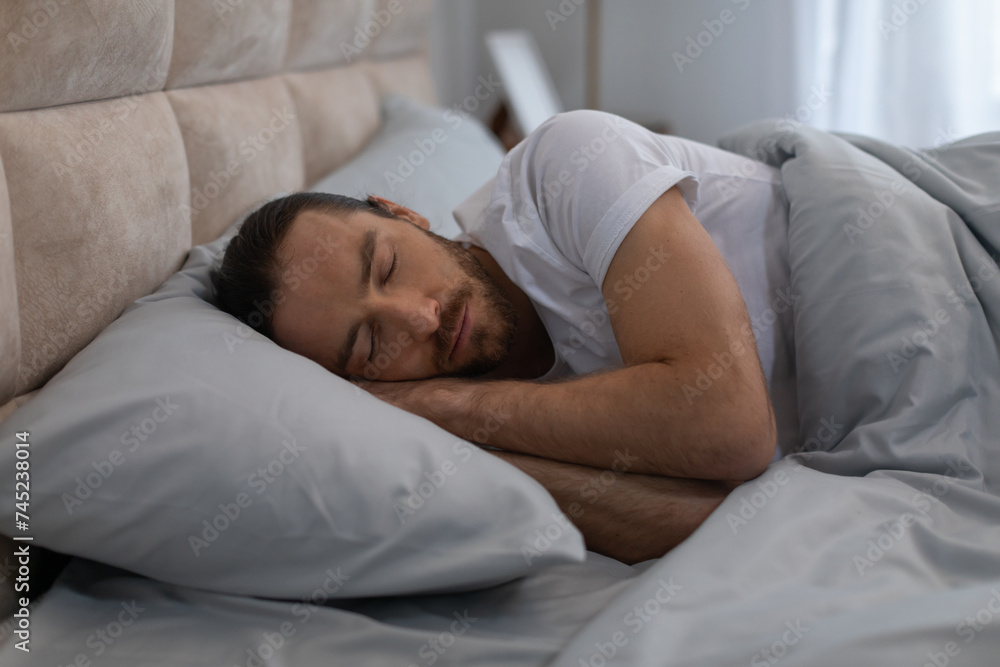 European man sleeping peacefully in cozy bed at home European man sleeping peacefully in cozy bed at home