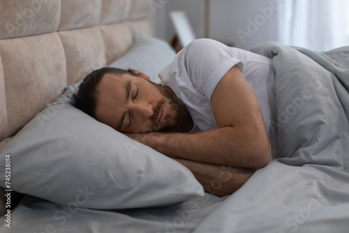European man sleeping peacefully in cozy bed at home
