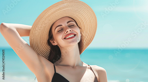 Radiant young woman in a swimsuit and sunhat, enjoying the sunshine on a serene beach.