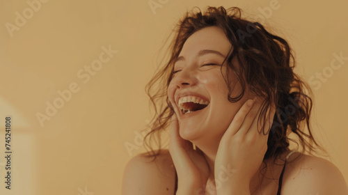 Radiant woman laughing wholeheartedly with hands on face.