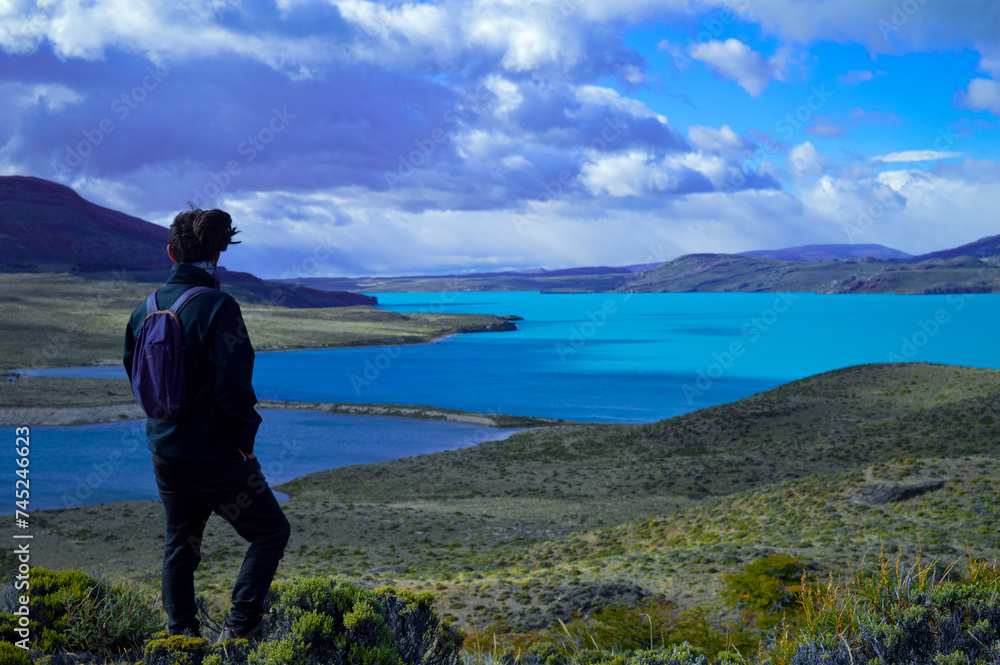 Hombre joven en diferentes paisajes, con montañas de fondo disfrutando de sus trekkings y senderos,  paisaje de lagos, montañas y colores