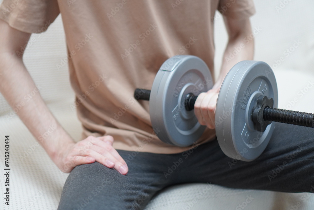 close-up of men's hands with dumbbells made of plastic for sports and muscle building of a European in a beige T-shirt, the concept of sports and an active image