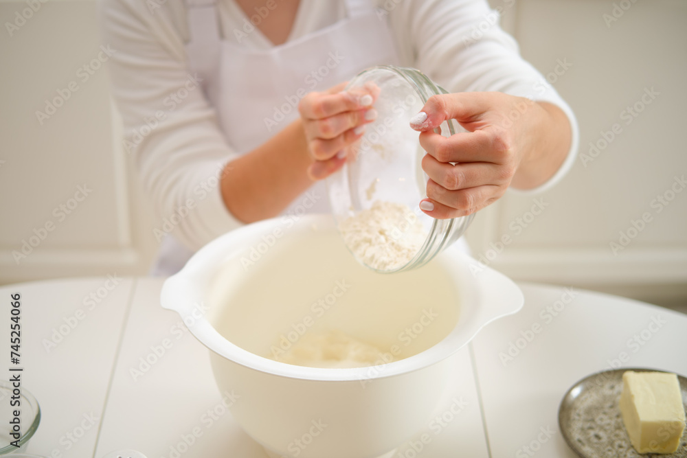 A woman pours flour into a bowl for making pie dough. Process of cooking pecan pie in home kitchen for American Thanksgiving Day. A woman pours flour into a bowl for making pie dough. Process of cooking pecan pie in home kitchen for American Thanksgiving Day.