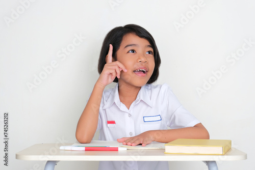 Indonesian kid student find new idea when sitting on school desk photo