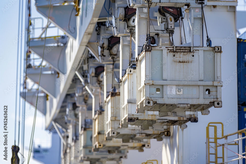 Close-up of the intricate machinery at the port as cargo containers are loaded onto a container ship, each container carefully stowed to ensure safe passage across the high seas.