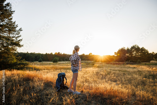 Woman tourist has found perfect place for camping outdoors before sunset. Hiking and trekking at summer nature