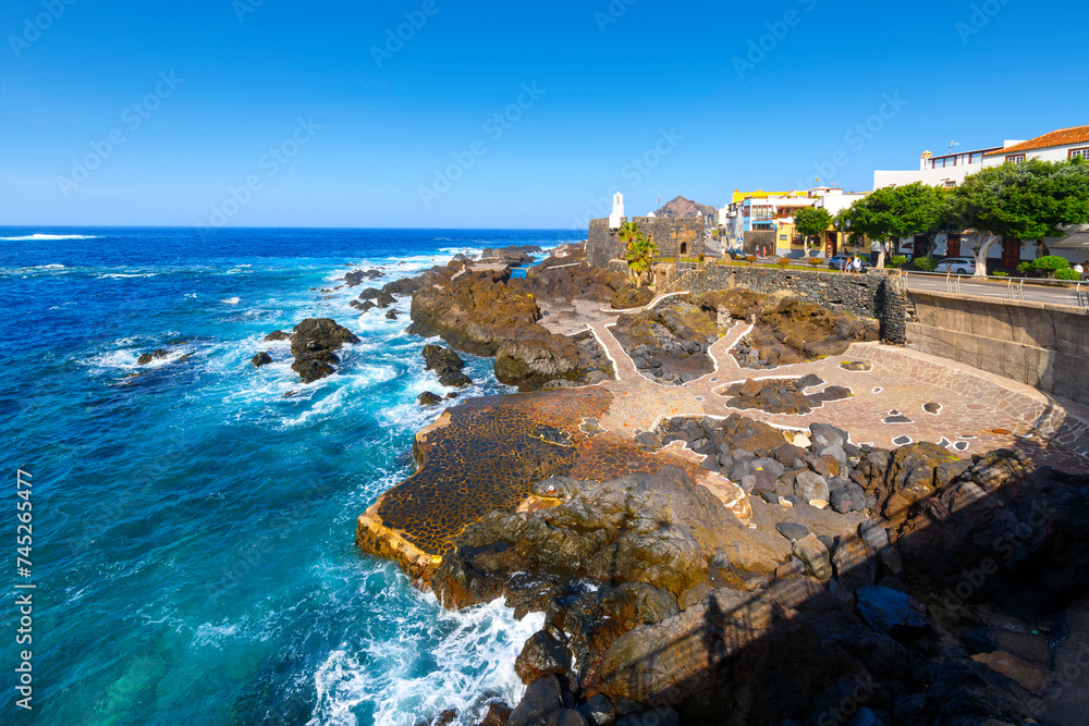 Obraz premium The volcanic rock coastline and blue turquoise water at the historic town of Garachico, Spain, on the Northern coast of Tenerife, an island in the Atlantic Ocean and part of the Canary Islands.