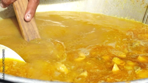 Close-up of a soto daging or beef soto vendor hand stirring a cauldron full of soto broth filled with offal using a strainer ladle. photo