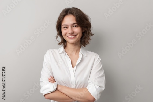 Smiling individual with folded arms, white shirt on grey background 