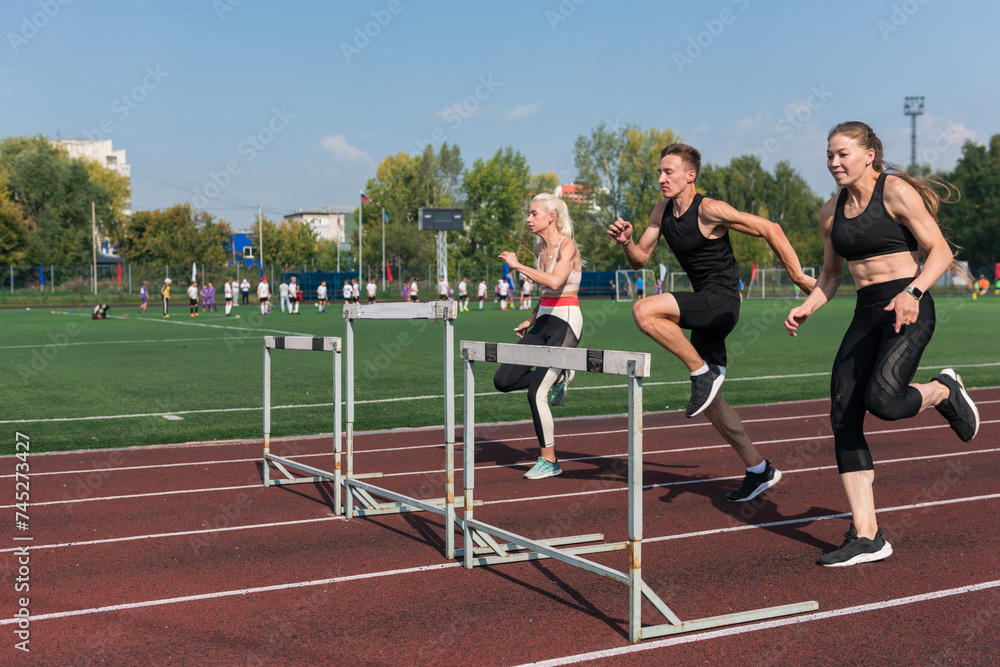 Obraz premium Two athlete woman and man runnner running hurdles
