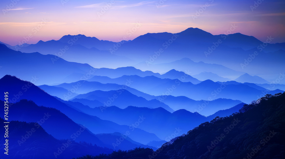 Blue mountain silhouettes layered in the fading light of dusk, evoking tranquility and vastness.