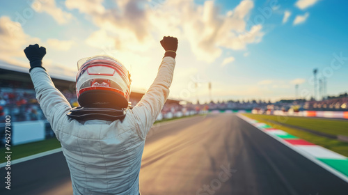 A victorious race winner, donned in a helmet, celebrates triumphantly on the race track, basking in the glory of their achievement amidst the cheers of the crowd.