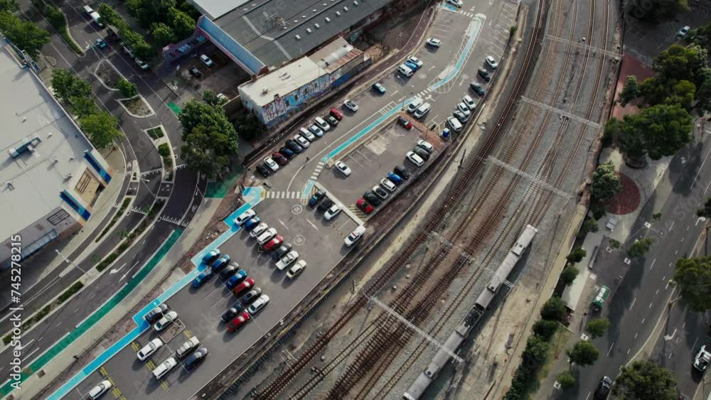 Aerial view capturing the bustling environment of a railway station parking lot. Various cars are neatly parked against a backdrop of multiple railway tracks, concept of urban setting with efficient Aerial view capturing the bustling environment of a railway station parking lot. Various cars are neatly parked against a backdrop of multiple railway tracks, concept of urban setting with efficient