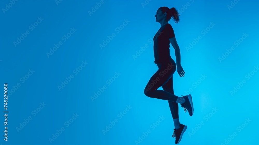 A female athlete in black sportswear Jumping over a blue background.