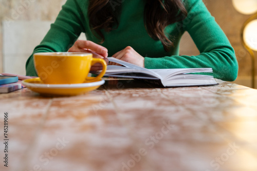 Woman sitting at a table with a hot drink reading a book photo